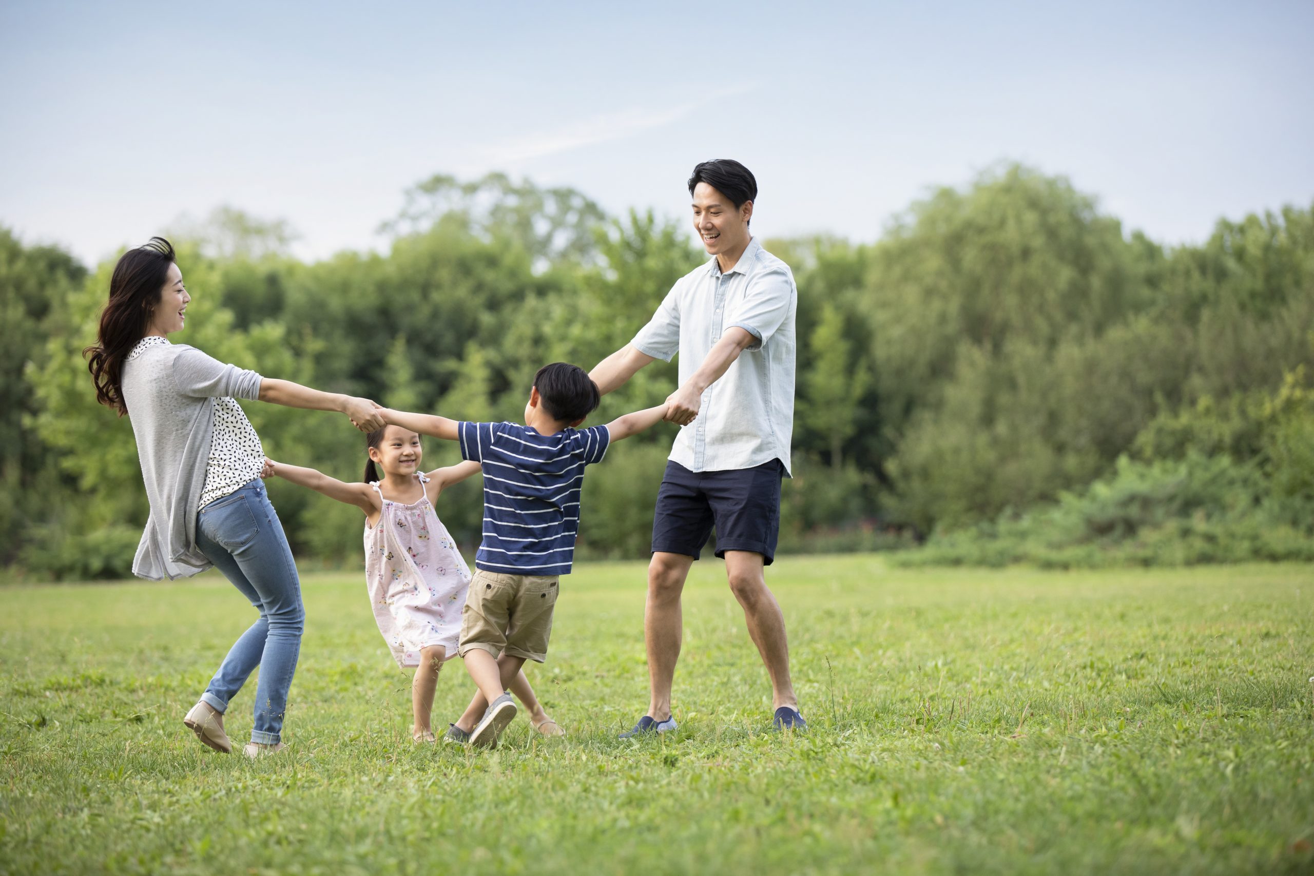 Happy Young Chinese Family Playing On Grass